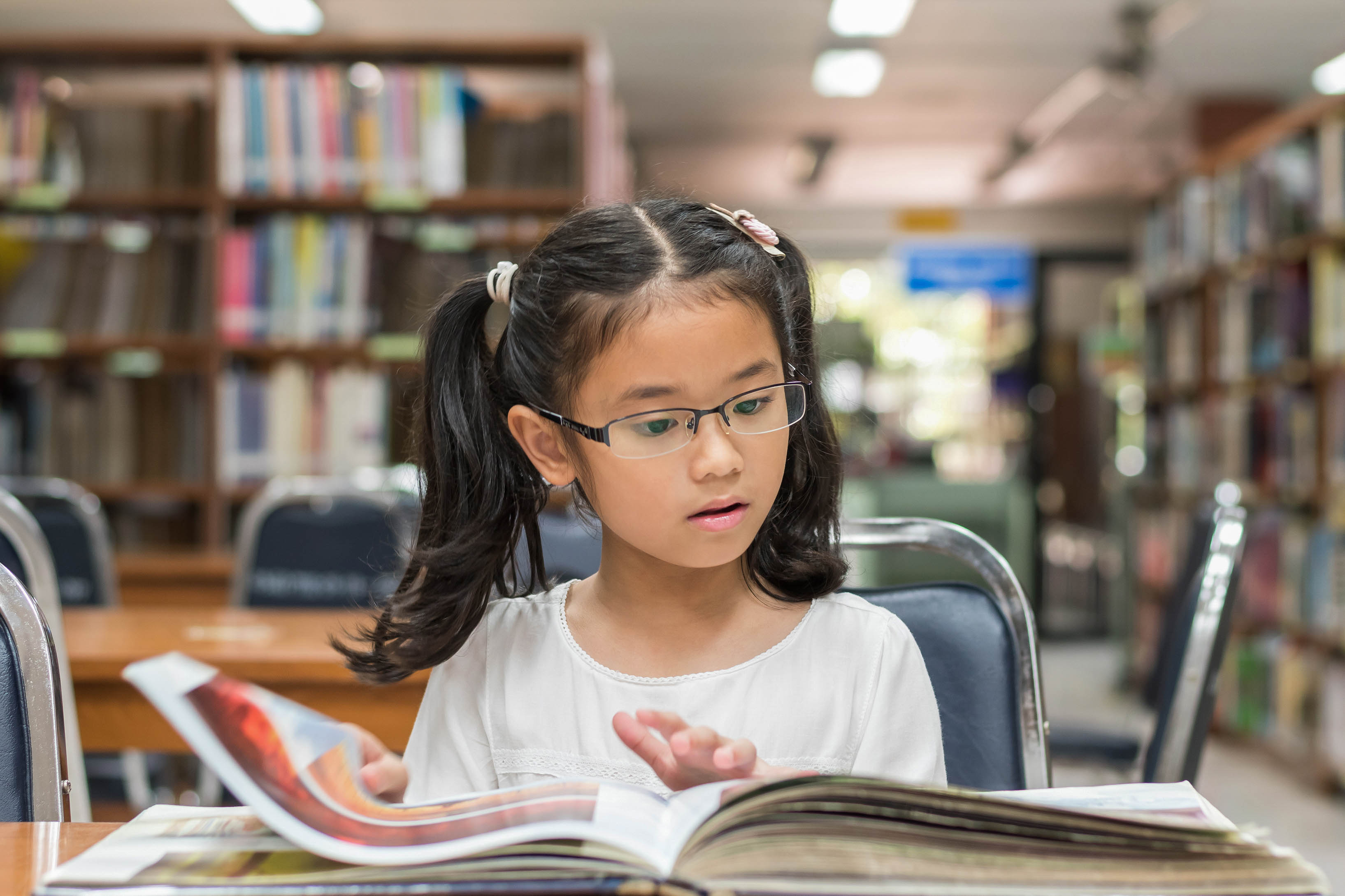 A child reads a book while flipping a page