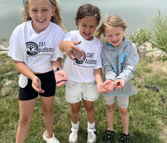 Three girls hold worms while fishing at Lake Elmo