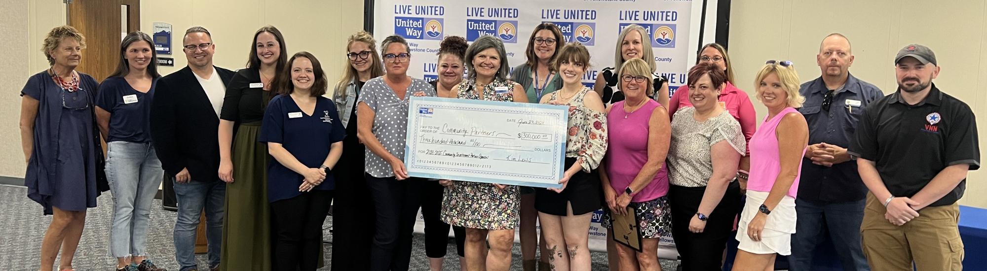 A group of non-profit leaders stand with then-UWYC president and CEO Kim Lewis and a big check representing total amounts granted to local non-profits. 
