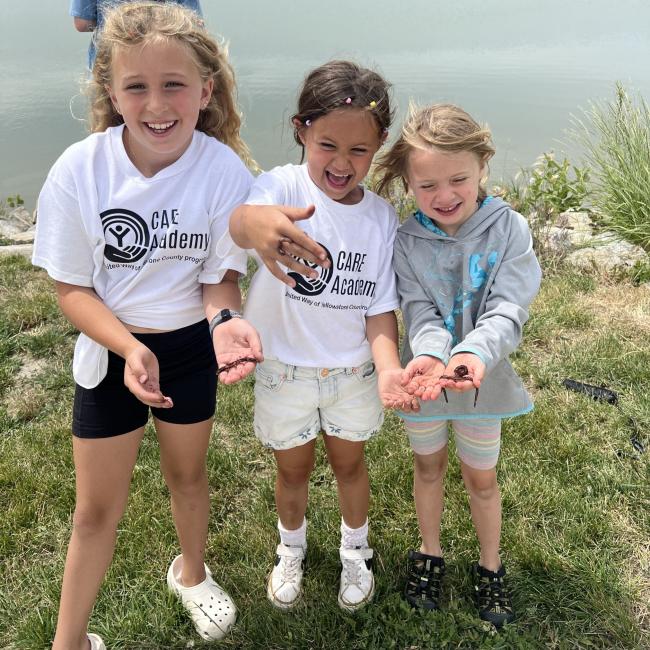 Three girls hold worms while fishing at Lake Elmo
