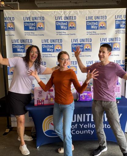 Three women pose while dropping off diapers for community diaper drive.