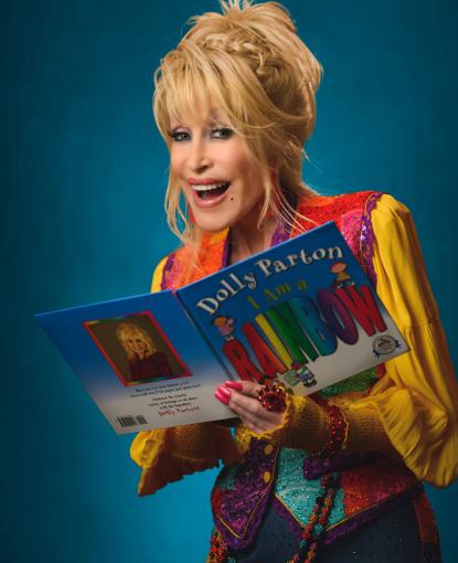 Dolly Parton holds a book and smiles.