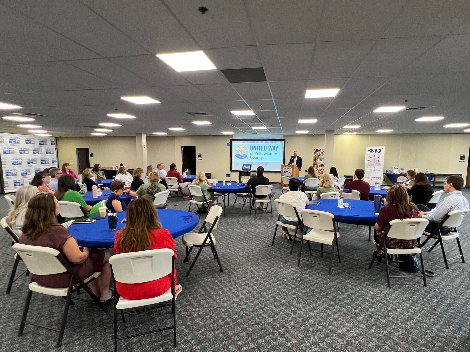 About 25 people sit at a group of round tables listening to UWYC CEO Andrew Konkel and the CHN announcement