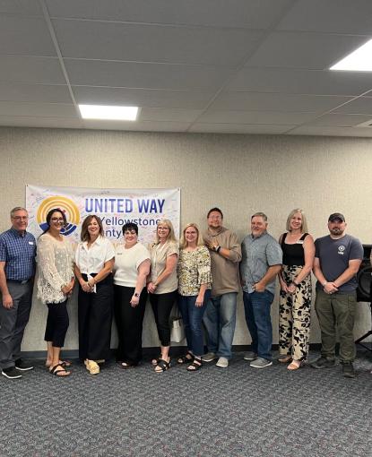 A group of people standing in front of a UWYC banner at the Community Investment Grant announcement